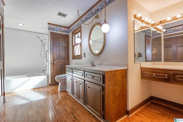 full bathroom with toilet, tiled shower / bath, hardwood / wood-style flooring, and vanity