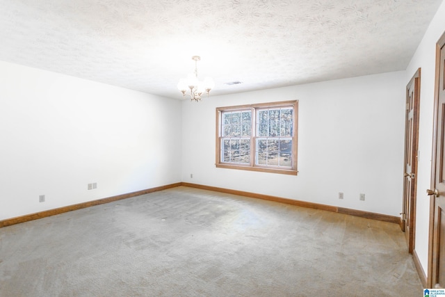 carpeted spare room with a textured ceiling and a chandelier