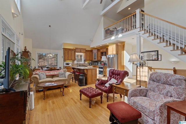 living room with a high ceiling, beam ceiling, and light wood-type flooring