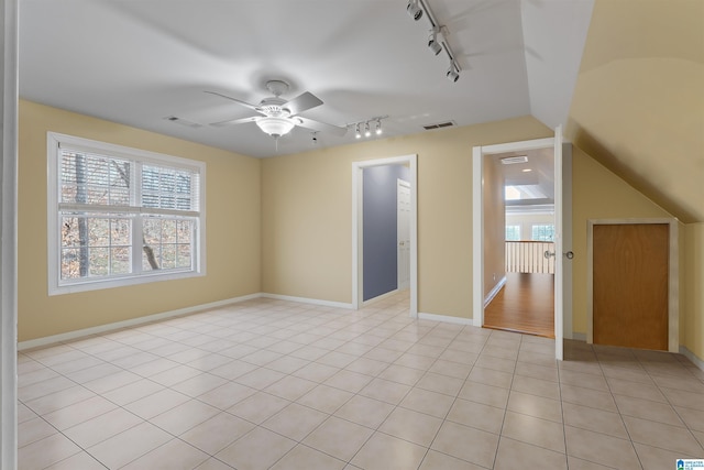 tiled empty room featuring lofted ceiling, ceiling fan, and rail lighting