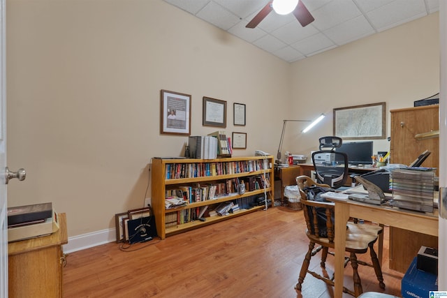 home office with light hardwood / wood-style floors, a drop ceiling, and ceiling fan