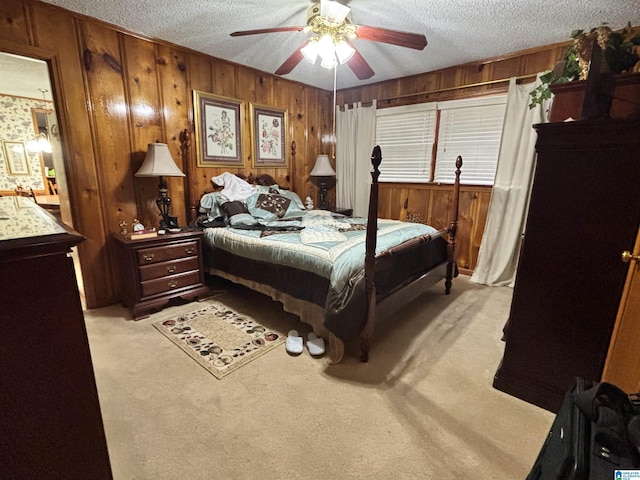 carpeted bedroom featuring a textured ceiling, ceiling fan, and wood walls