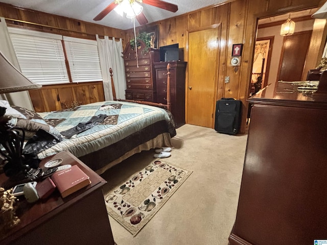 carpeted bedroom featuring ceiling fan and wooden walls