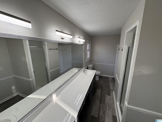 bathroom with hardwood / wood-style floors, an enclosed shower, vanity, and a textured ceiling