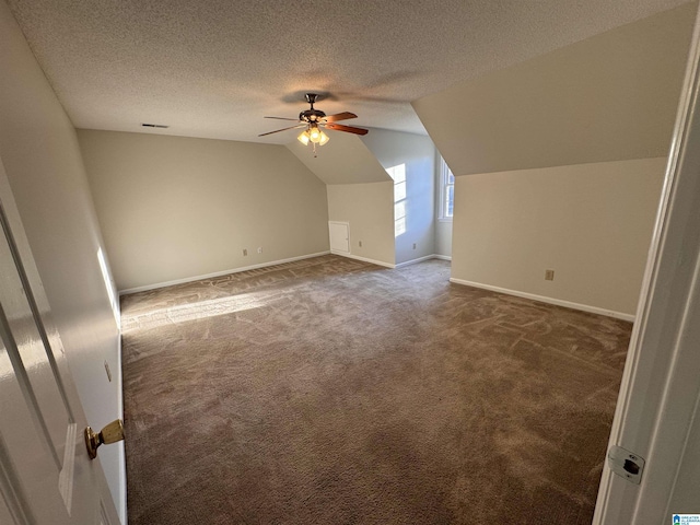 additional living space with ceiling fan, vaulted ceiling, a textured ceiling, and dark colored carpet