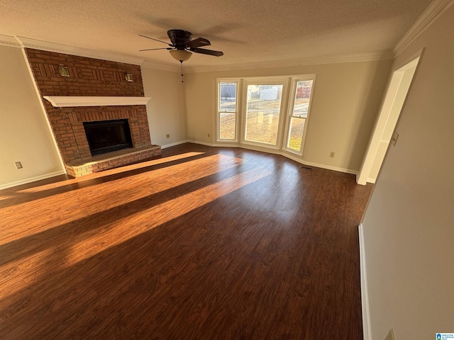 unfurnished living room featuring a brick fireplace, ceiling fan, dark wood-type flooring, a textured ceiling, and ornamental molding