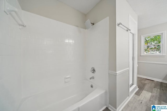 bathroom featuring hardwood / wood-style flooring, tub / shower combination, and a textured ceiling