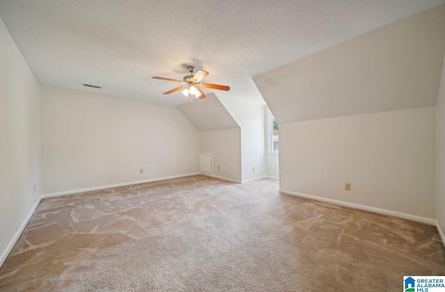 additional living space with ceiling fan, light colored carpet, a textured ceiling, and lofted ceiling