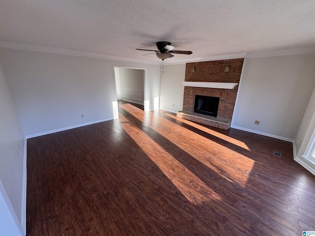 unfurnished living room with a textured ceiling, a brick fireplace, ornamental molding, and dark hardwood / wood-style flooring