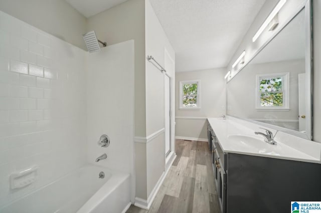 bathroom with shower / washtub combination, a textured ceiling, wood-type flooring, and vanity