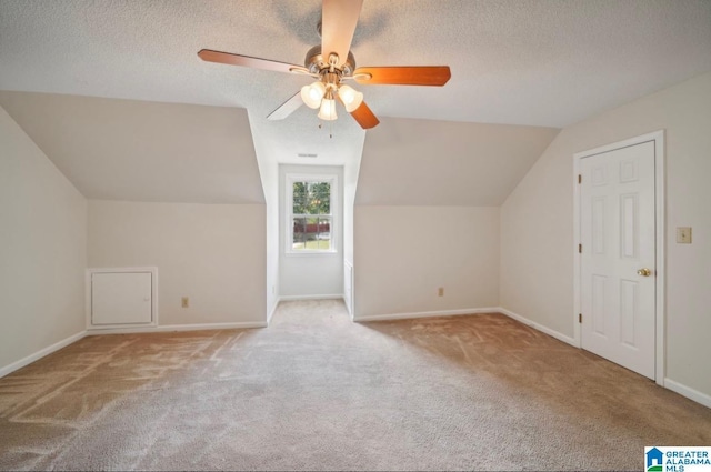 additional living space featuring light carpet, ceiling fan, lofted ceiling, and a textured ceiling