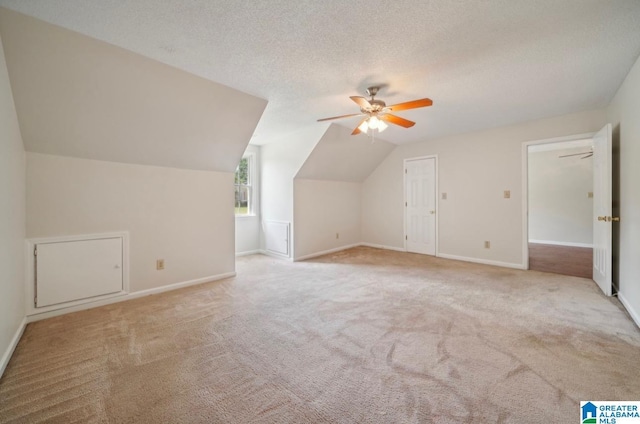 bonus room featuring light carpet, vaulted ceiling, a textured ceiling, and ceiling fan