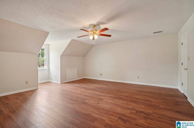 additional living space with ceiling fan, vaulted ceiling, dark hardwood / wood-style floors, and a textured ceiling