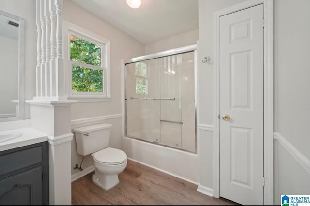 full bathroom featuring toilet, bath / shower combo with glass door, wood-type flooring, and vanity