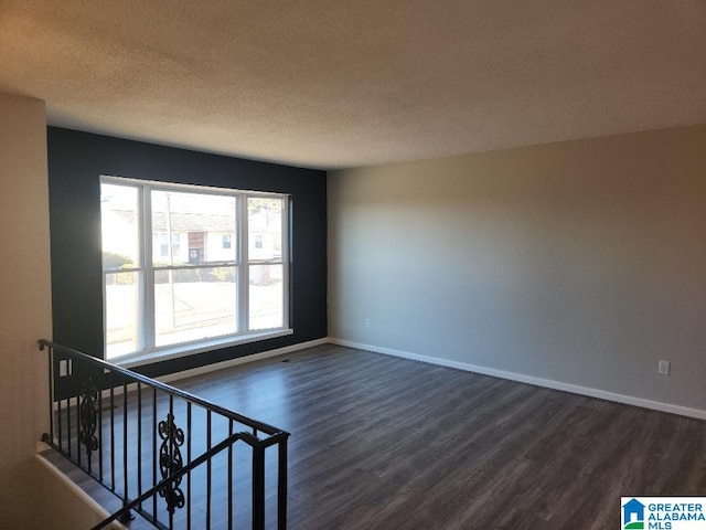 empty room with a textured ceiling and dark hardwood / wood-style flooring