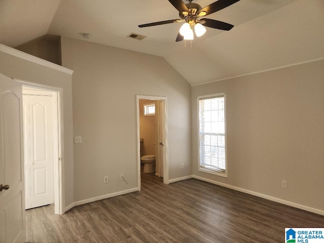 unfurnished bedroom featuring ceiling fan, dark wood-type flooring, ensuite bath, and vaulted ceiling