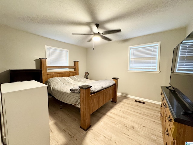 bedroom featuring light wood-type flooring, ceiling fan, and a textured ceiling