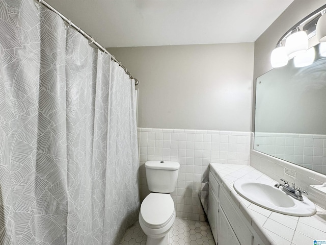 bathroom featuring toilet, tile patterned flooring, tile walls, and vanity