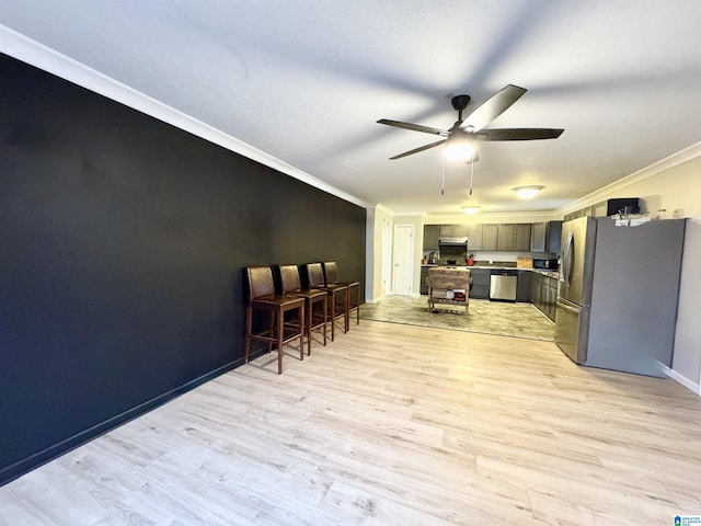 kitchen with ceiling fan, appliances with stainless steel finishes, ornamental molding, and light hardwood / wood-style flooring