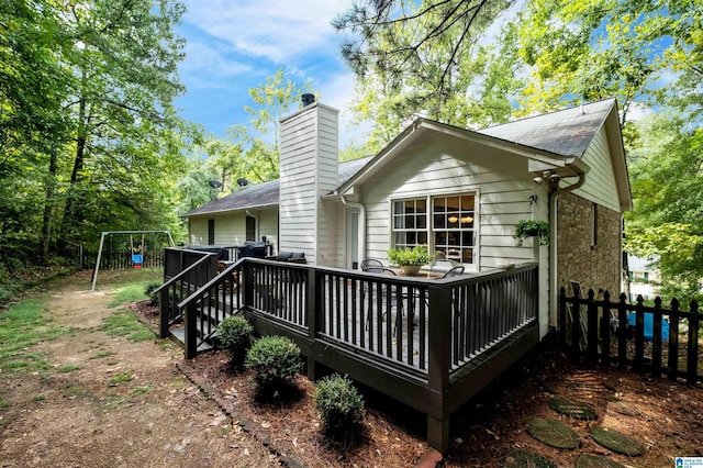 back of property featuring a playground and a wooden deck