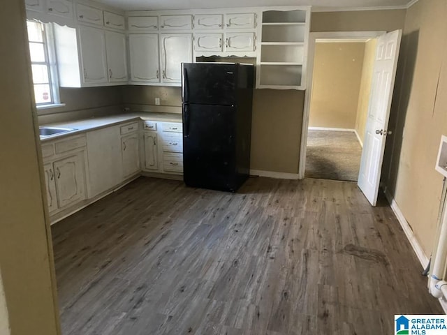 kitchen with light hardwood / wood-style floors, black refrigerator, and white cabinetry