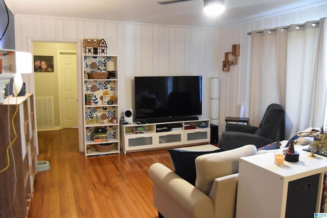 living room featuring ceiling fan, wood-type flooring, wood walls, and crown molding