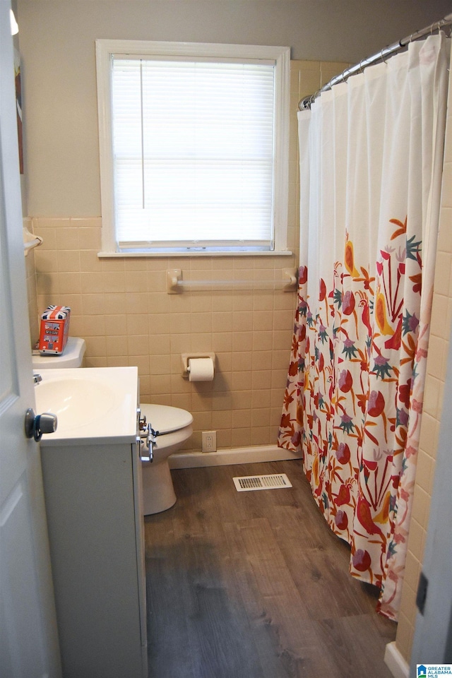 bathroom with hardwood / wood-style floors, vanity, tile walls, toilet, and walk in shower