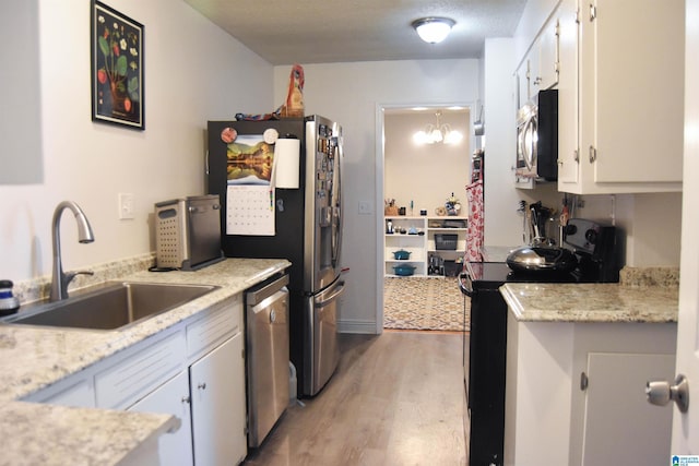 kitchen featuring stainless steel appliances, white cabinets, a chandelier, light hardwood / wood-style flooring, and sink