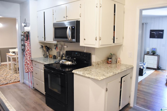 kitchen with white cabinets, black electric range oven, and light wood-type flooring