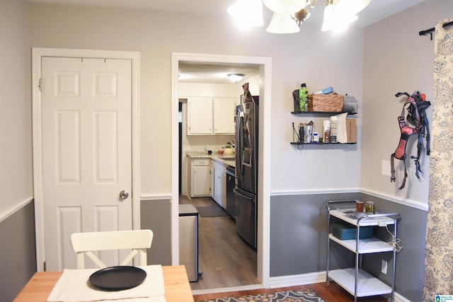 interior space featuring white cabinetry, dark hardwood / wood-style floors, a notable chandelier, stainless steel refrigerator, and dishwashing machine