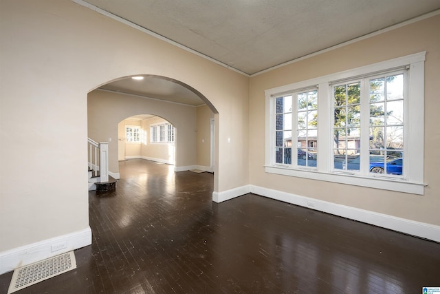 empty room with a textured ceiling, dark hardwood / wood-style floors, and crown molding