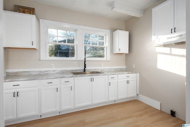 kitchen featuring beamed ceiling, sink, light hardwood / wood-style flooring, light stone countertops, and white cabinets