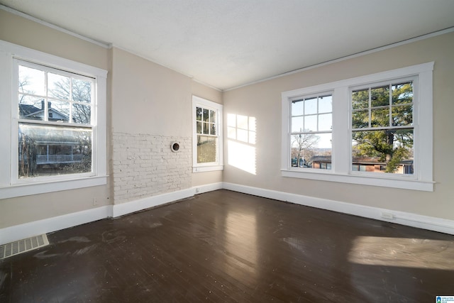 empty room with dark wood-type flooring, a wealth of natural light, and crown molding