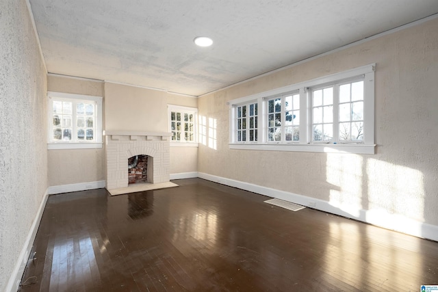 unfurnished living room with a brick fireplace, dark hardwood / wood-style floors, and ornamental molding