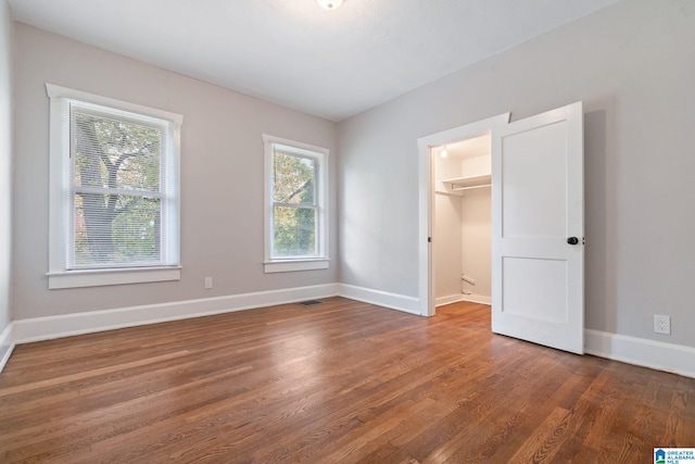 unfurnished bedroom with dark hardwood / wood-style flooring, a closet, and a walk in closet