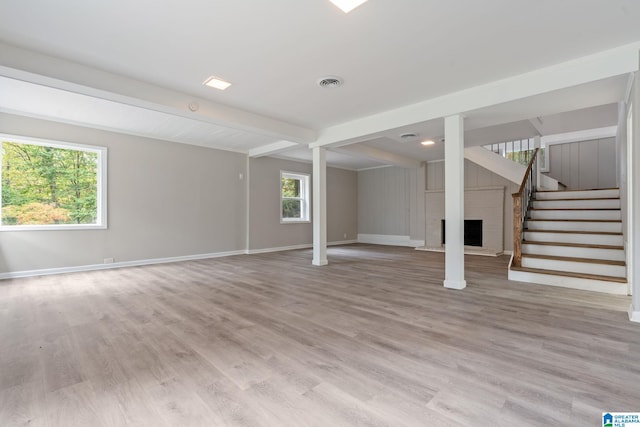 basement featuring a brick fireplace and light hardwood / wood-style flooring