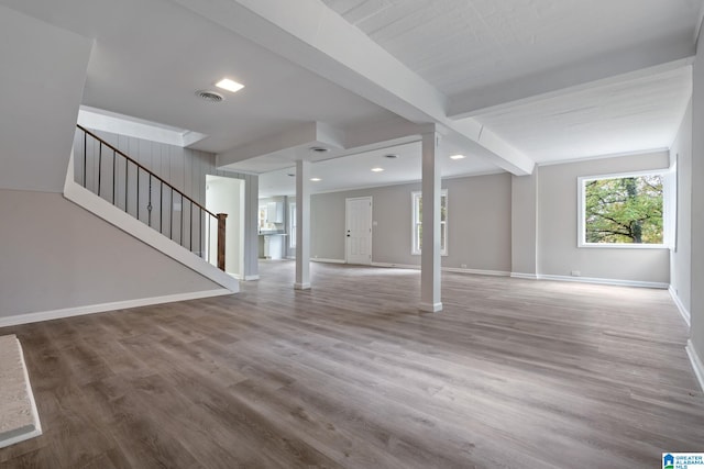 unfurnished living room featuring wood-type flooring and beam ceiling