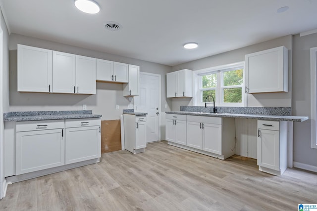 kitchen featuring white cabinets, light wood-type flooring, and sink