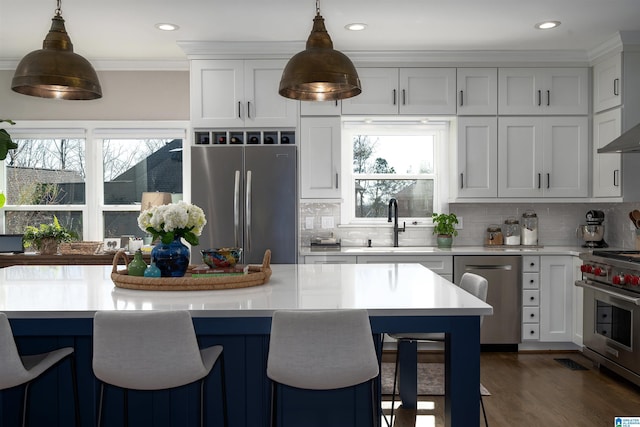 kitchen with pendant lighting, backsplash, white cabinetry, and appliances with stainless steel finishes