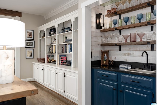 bar with sink, dark wood-type flooring, blue cabinetry, ornamental molding, and white cabinets