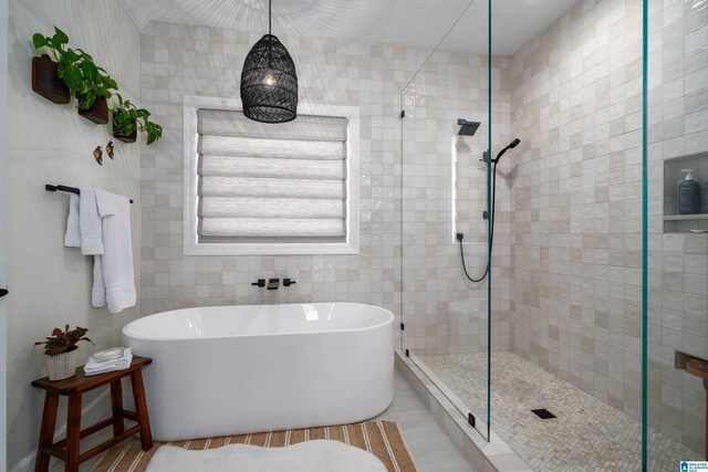 bathroom with tile walls and independent shower and bath