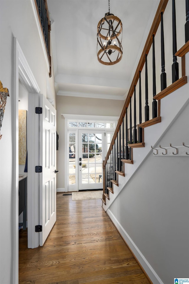 foyer entrance with dark hardwood / wood-style floors, crown molding, and a chandelier