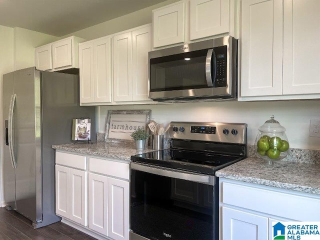 kitchen with light stone countertops, white cabinetry, and stainless steel appliances