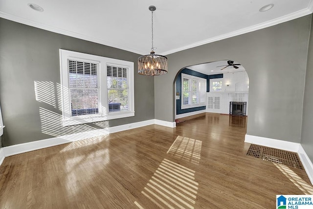 unfurnished living room with ornamental molding, ceiling fan with notable chandelier, and wood-type flooring