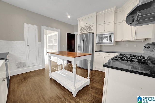 kitchen with dark hardwood / wood-style floors, ventilation hood, appliances with stainless steel finishes, and white cabinets