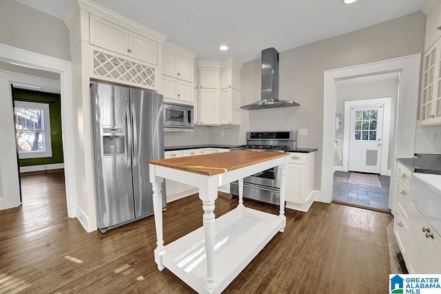 kitchen with white cabinets, wall chimney exhaust hood, stainless steel appliances, and a healthy amount of sunlight