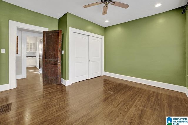 unfurnished bedroom featuring dark wood-type flooring, ceiling fan, and a closet