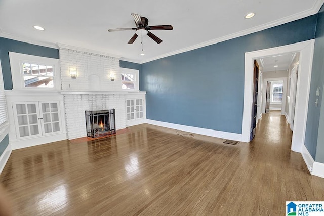 unfurnished living room featuring ceiling fan, a fireplace, crown molding, and hardwood / wood-style floors