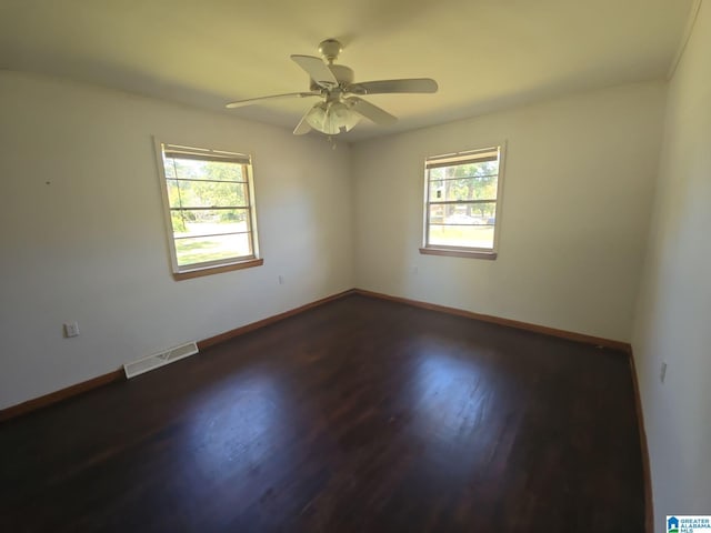 spare room featuring ceiling fan, a wealth of natural light, and dark hardwood / wood-style floors