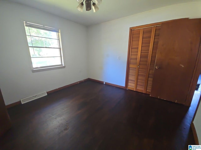 unfurnished bedroom featuring a closet, dark hardwood / wood-style flooring, and ceiling fan